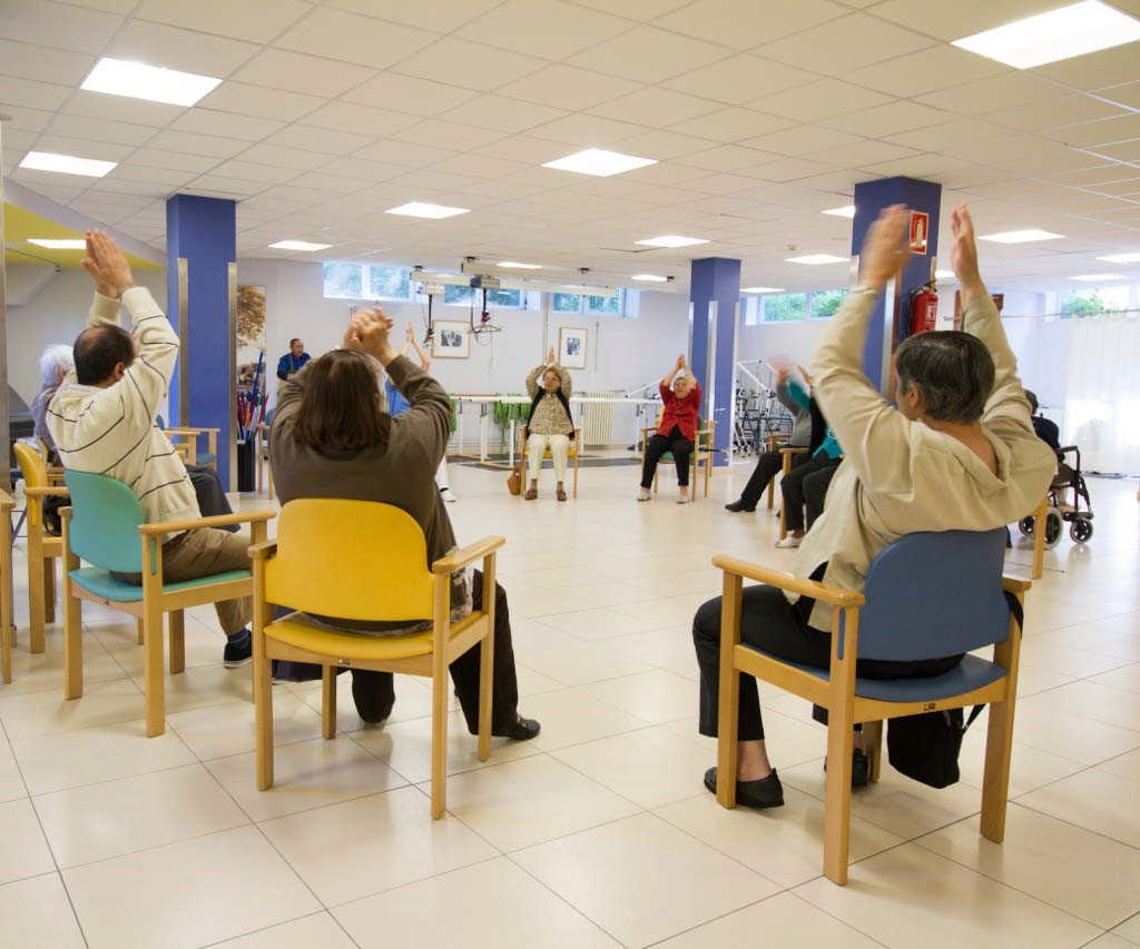 personas mayores sentadas en cículo haciendo ejercicios en el centro de día