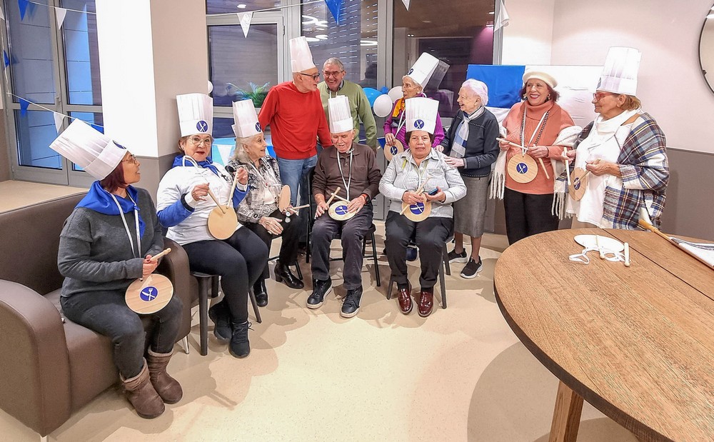 un grupo de residentes toca el tambor al ritmo d ela marcha de San Sebastián ataviado con gorros de cocinero