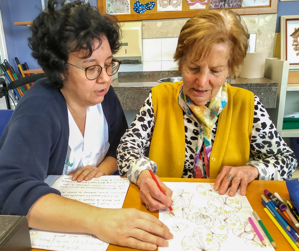 una resdente dibuja con la ayuda de una auxiliar