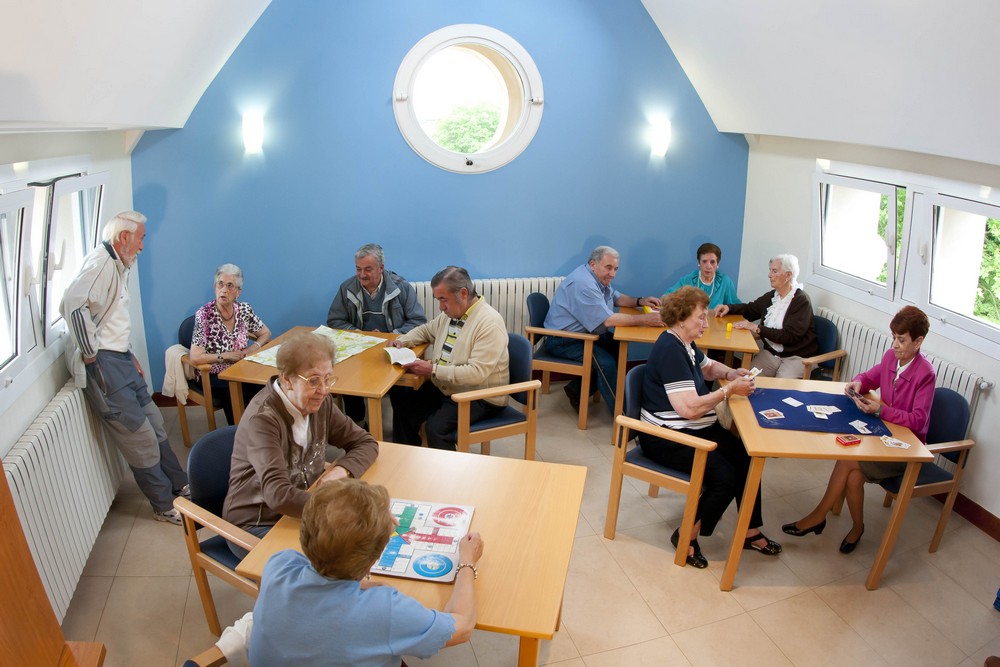 Salón común de las viviendas comunitarias con residentes charlando y jugando.